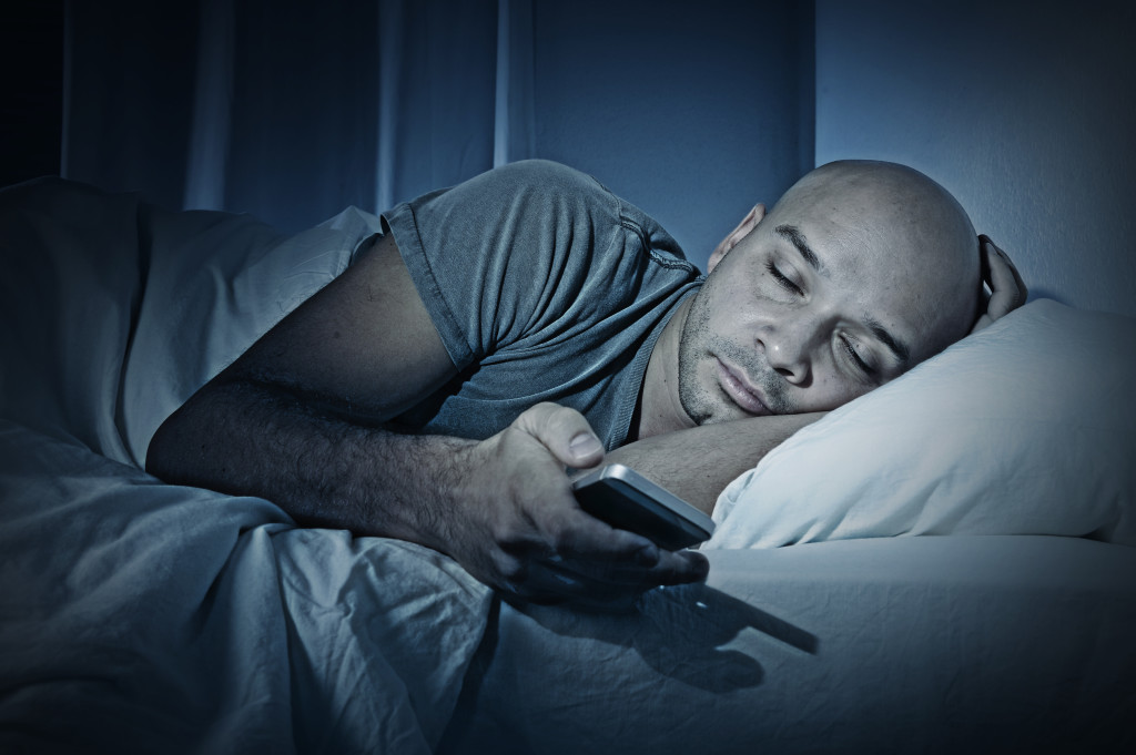 Young Cell Phone Addict Man Sleeping At Night In Bed While Using